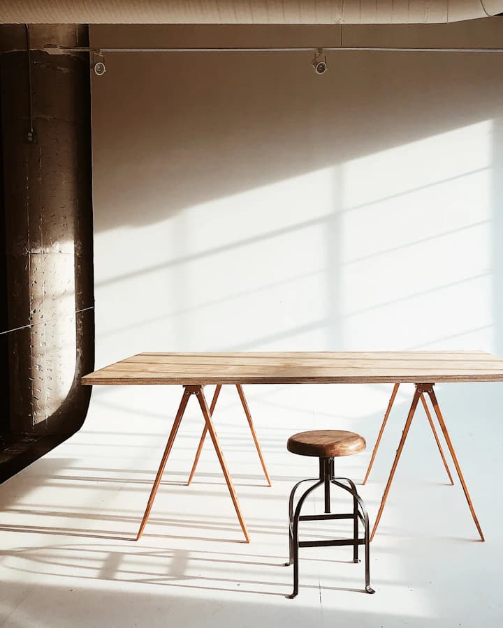 Table en chêne massif sur tréteaux fins dans un atelier baigné de lumière